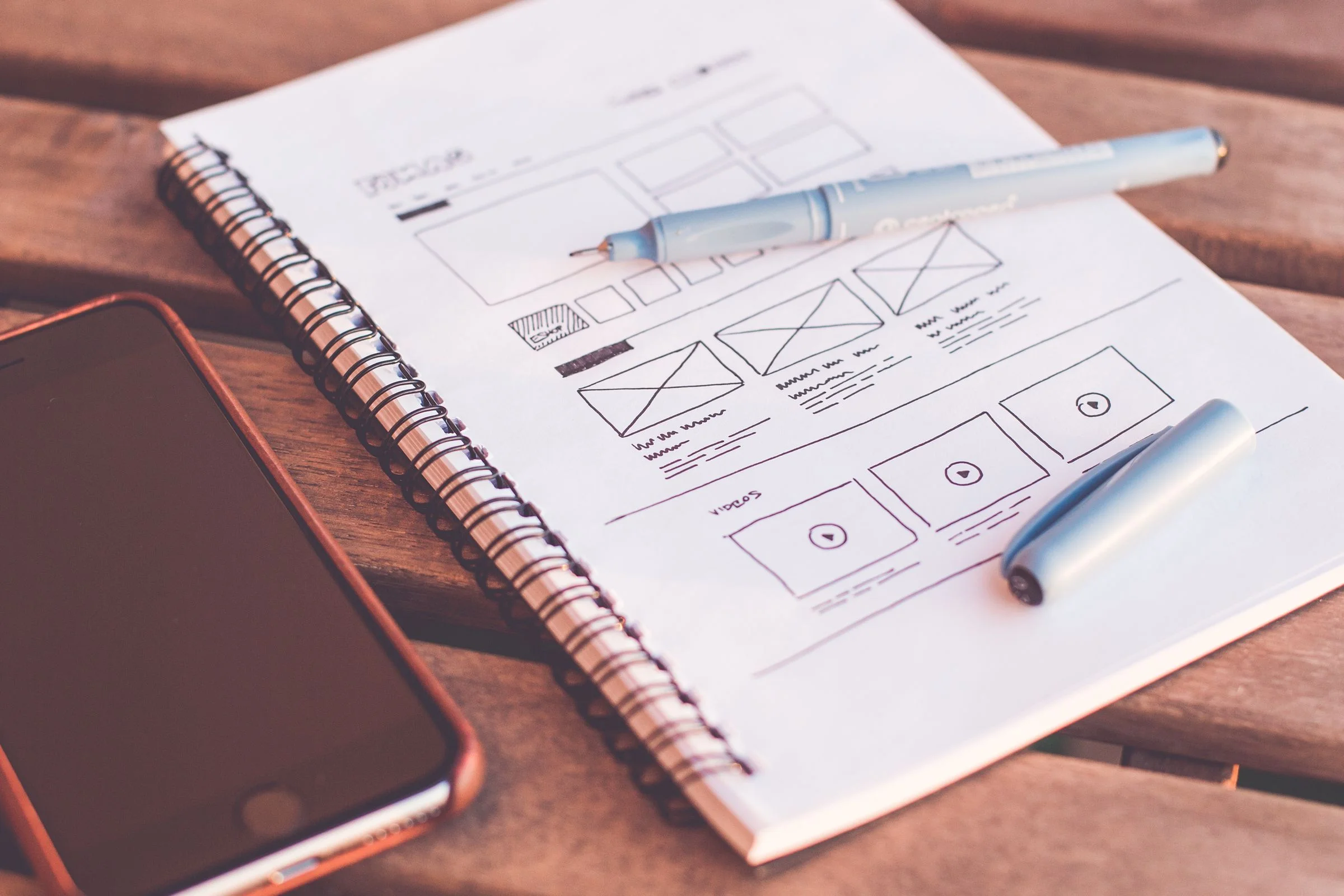 Notesbog med håndtegnede website-wireframes til UX/UI
